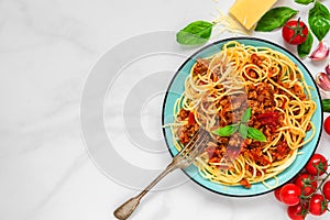 Pasta spaghetti bolognese on a blue plate with fork on white marble table. healthy food. top view