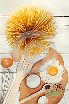 Pasta spaghetti with flour, egg on rustic wooden background