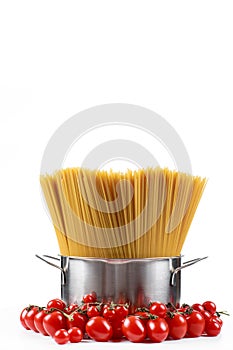 Pasta spaghetti in a metal pan in a large collum on a white background with tomatoes.