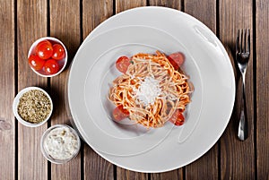 Pasta Spaghetti with olive oil, cheese, herbs and tomatoes on wooden background