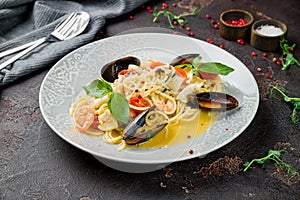 Pasta spaghetti with seafood, shrimps, mussels, tomatoes and basil on dark concrete table