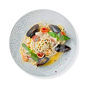 Pasta spaghetti with seafood, shrimps, mussels, tomatoes and basil isolated on white top view