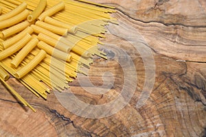 Pasta, spaghetti and sedani on an olive wood cutting board