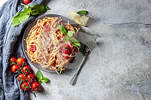 Pasta, spaghetti with tomato sauce, cherry tomatoes, fresh basil on a white concrete background.