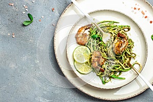 Pasta spaghetti zucchini basil pesto sauce and grilled shrimp, Vegetarian vegetable pasta, Food recipe background. Close up