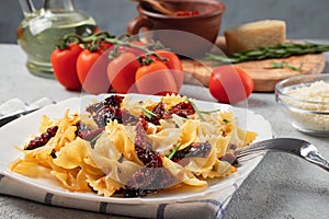 Pasta with sun-dried tomatoes and parmesan in a white plate on the table. Italian cuisine, ingredients and the finished