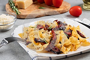 Pasta with sun-dried tomatoes and parmesan in a white plate on the table. Italian cuisine, ingredients and the finished