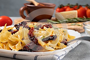 Pasta with sun-dried tomatoes and parmesan in a white plate on the table. Italian cuisine, ingredients and the finished