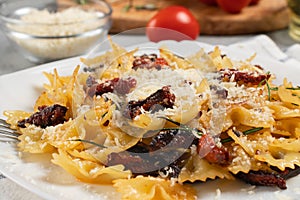 Pasta with sun dried tomatoes and parmesan in a white plate on the table. Italian food dish, close up