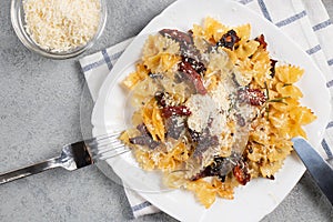 Pasta with sun dried tomatoes and parmesan in a white plate on the table. Italian food dish, top view, flat lay