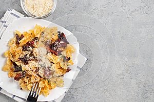 Pasta with sun dried tomatoes and parmesan in a white plate on the table. Italian food dish, top view, flat lay, copy