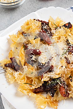 Pasta with sun dried tomatoes and parmesan in a white plate on the table. Italian food dish, vertical image