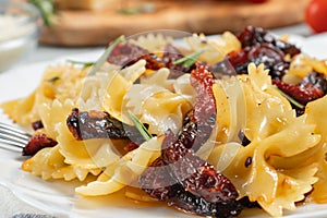 Pasta with sun-dried tomatoes in a white plate on the table. Italian food dish, close-up