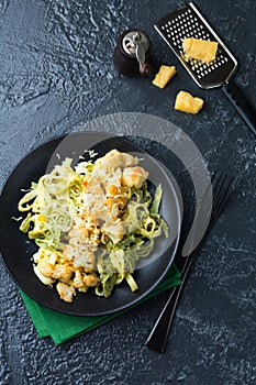 Pasta Tagliatelle in creamy sauce with baked cauliflower in a plate on a dark background. Selective focus.Top view
