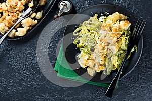 Pasta Tagliatelle in creamy sauce with baked cauliflower in a plate on a dark background. Selective focus.Top view