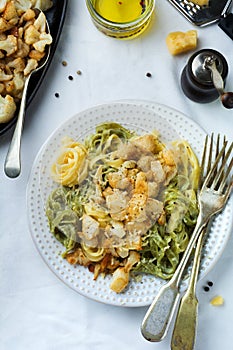 Pasta Tagliatelle in creamy sauce with baked cauliflower in a plate on a light background. Selective focus