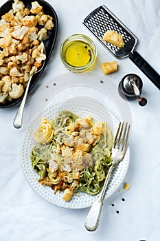 Pasta Tagliatelle in creamy sauce with baked cauliflower in a plate on a light background. Selective focus