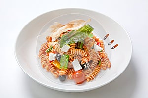 Pasta in tomato sauce with fried vegetables and fresh cherry tomatoes and feta