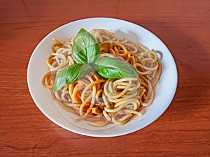 Pasta with tomato sauce, green basil, white plate