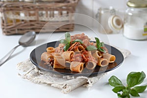 Pasta with tomato sauce and mackerel garnished with basil leaf