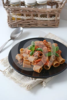 Pasta with tomato sauce and mackerel garnished with basil leaf