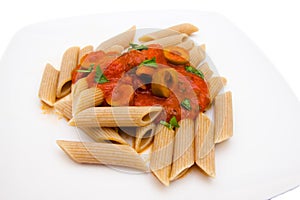 Pasta with tomato sauce and olives close up view