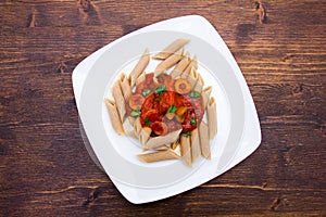 Pasta with tomato sauce and olives on wood from above