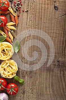 Pasta tomatoes basil frame on wooden background