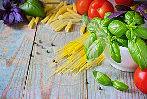 Pasta, tomatoes, and basil on wooden background
