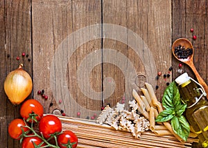 Pasta, tomatoes, onion, olive oil and basil on wooden background