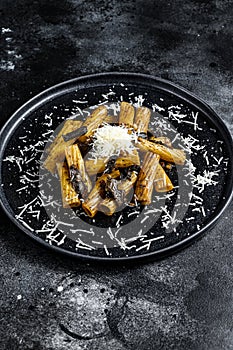 Pasta tortiglioni with black truffle and Boletus edulis, white mushroom. Black background. Top view. Space for text