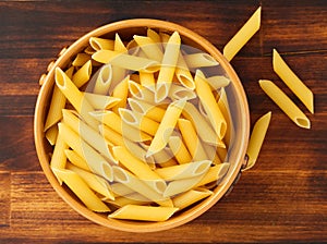 Pasta Tortiglioni in brown bowl on dark wooden brown table. Top view.