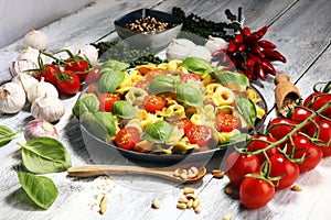 Pasta. tricolor tortellini pasta salad with tomatoes and onions on wood table background