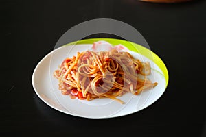 Pasta with vegetable sauce on a white porcelain plate on a black table