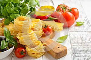 Pasta, vegetables, herbs and spices for Italian food on white wooden background