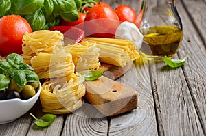 Pasta, vegetables, herbs and spices for Italian food on white wooden background