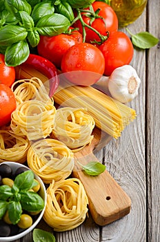 Pasta, vegetables, herbs and spices for Italian food on white wooden background