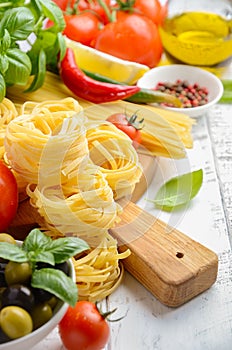 Pasta, vegetables, herbs and spices for Italian food on white wooden background