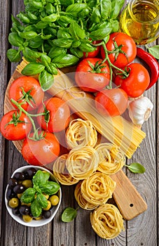 Pasta, vegetables, herbs and spices for Italian food on wooden background