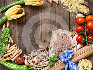 Pasta, vegetables and herbs on wood