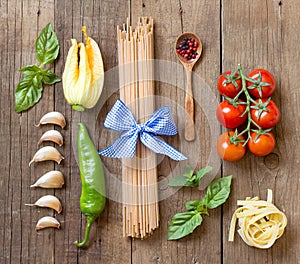 Pasta, vegetables and herbs on wood