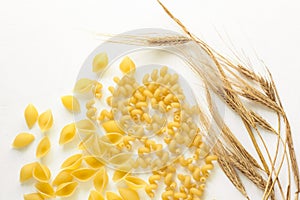 Pasta and wheat spikelets on a white background. Italian food recipes. Top view, flatlay, copy space