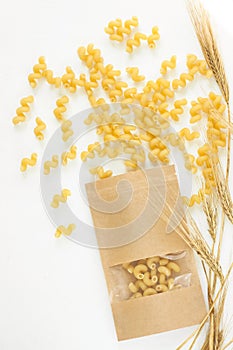 Pasta and wheat spikelets on a white background. Italian food recipes. Top view, flatlay, copy space