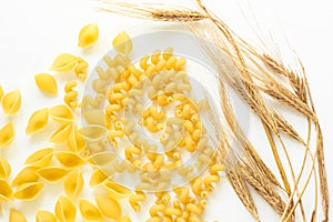 Pasta and wheat spikelets on a white background. Italian food recipes. Top view, flatlay, copy space