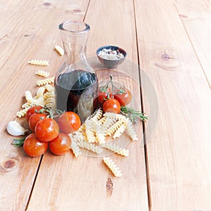 Pasta, wine, tomatoes and spices on a wooden