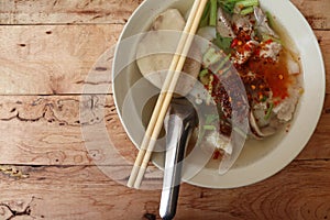 Paste of rice flour with spoon and chopsticks in the bowl isolated on wooden background closeup.