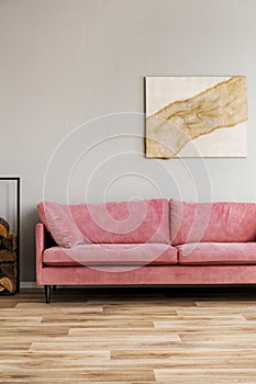 Pastel abstract painting on beige wall behind velvet pink settee in simple living room