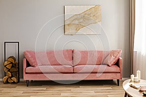 Pastel abstract painting on beige wall behind velvet pink settee in simple living room