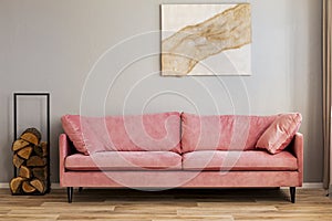 Pastel abstract painting on beige wall behind velvet pink settee in simple living room photo