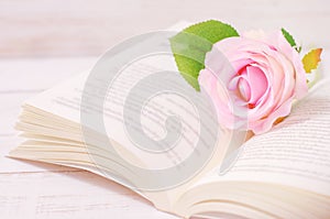 Pastel artificial rose and open book with vintage tone